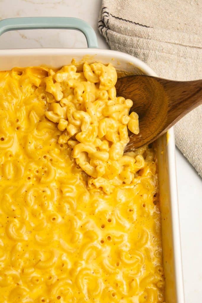 Velveeta baked mac and cheese recipe in a baking dish and a wooden spoon.