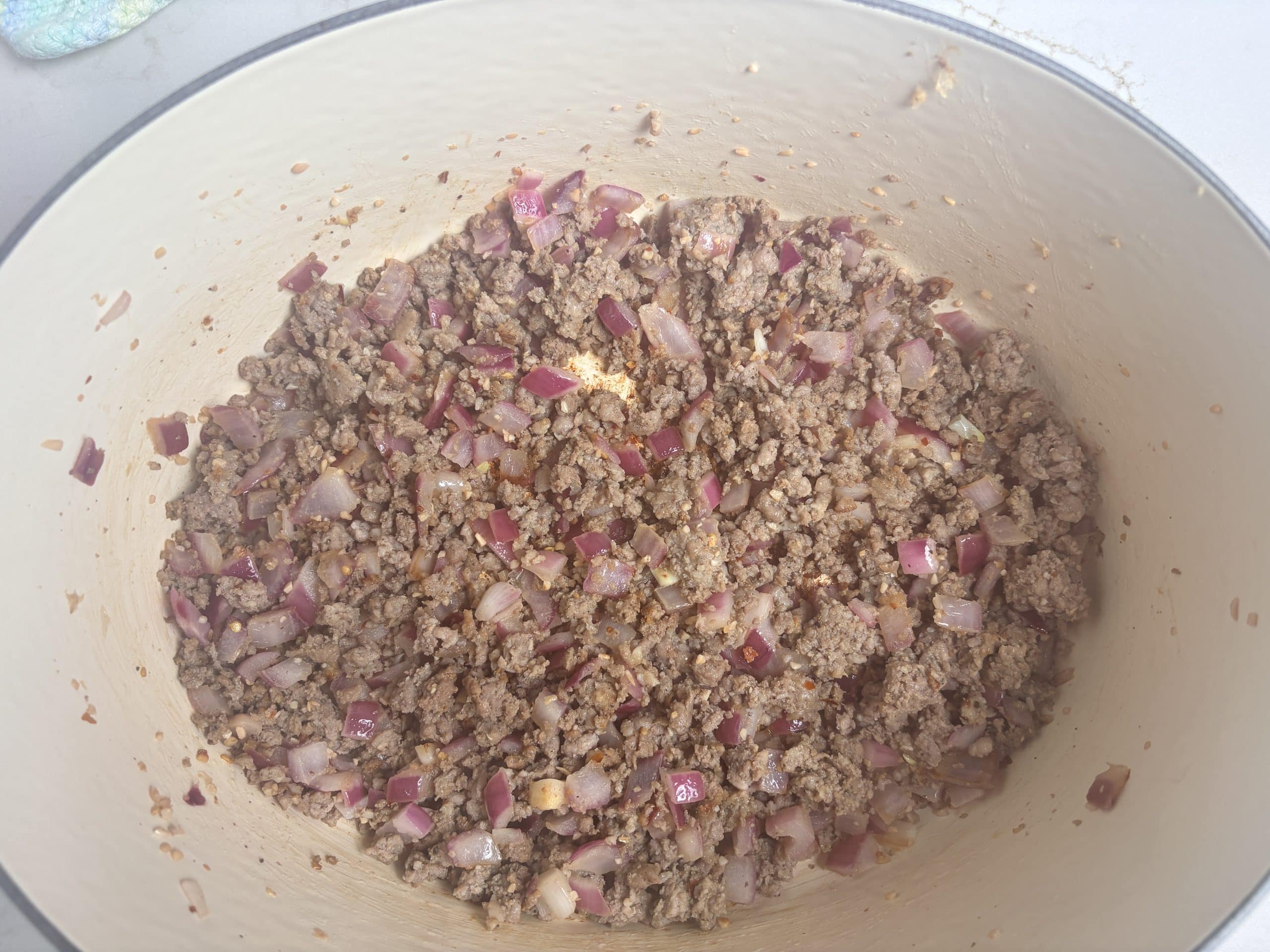 Ground sausage, onions, and garlic in an oval enameled Dutch Oven.
