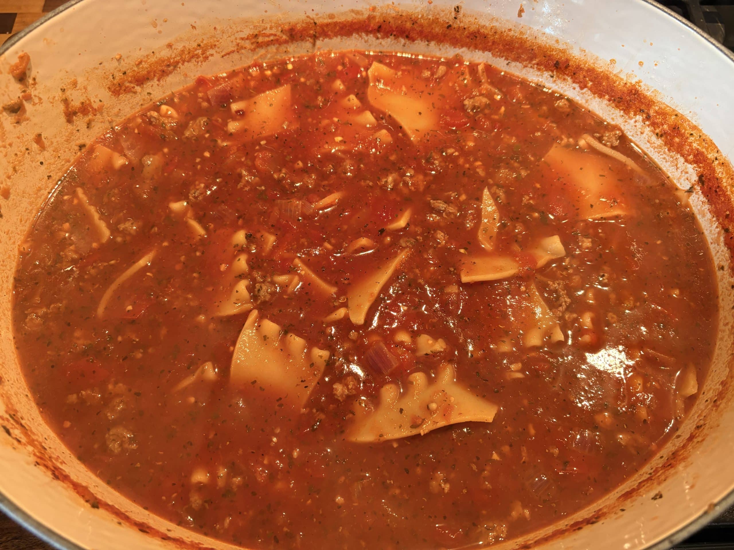 An oval enameled Dutch Oven filled with lasagna soup.