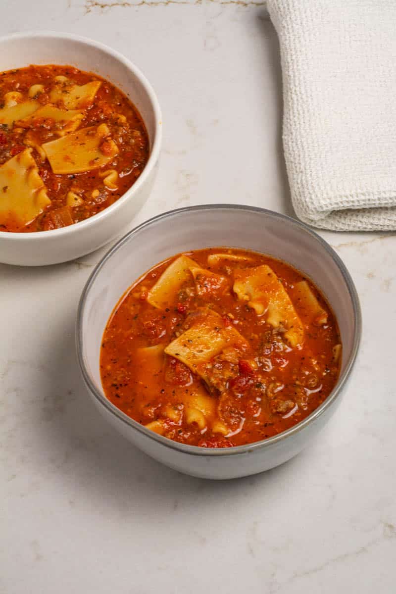 Two round bowls filled with one-pot lasagna soup on a marble table.