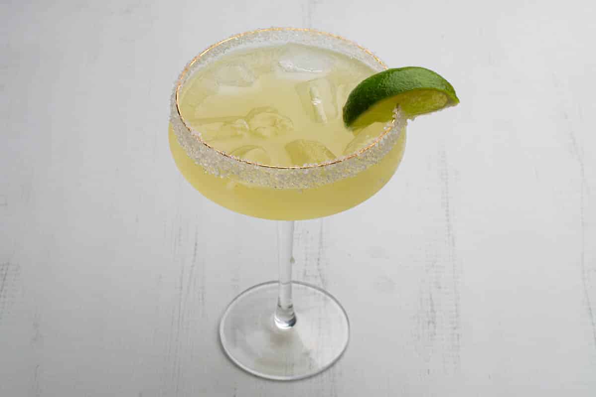 An agave margarita in a tall margarita glass with a lime wedge garnish.