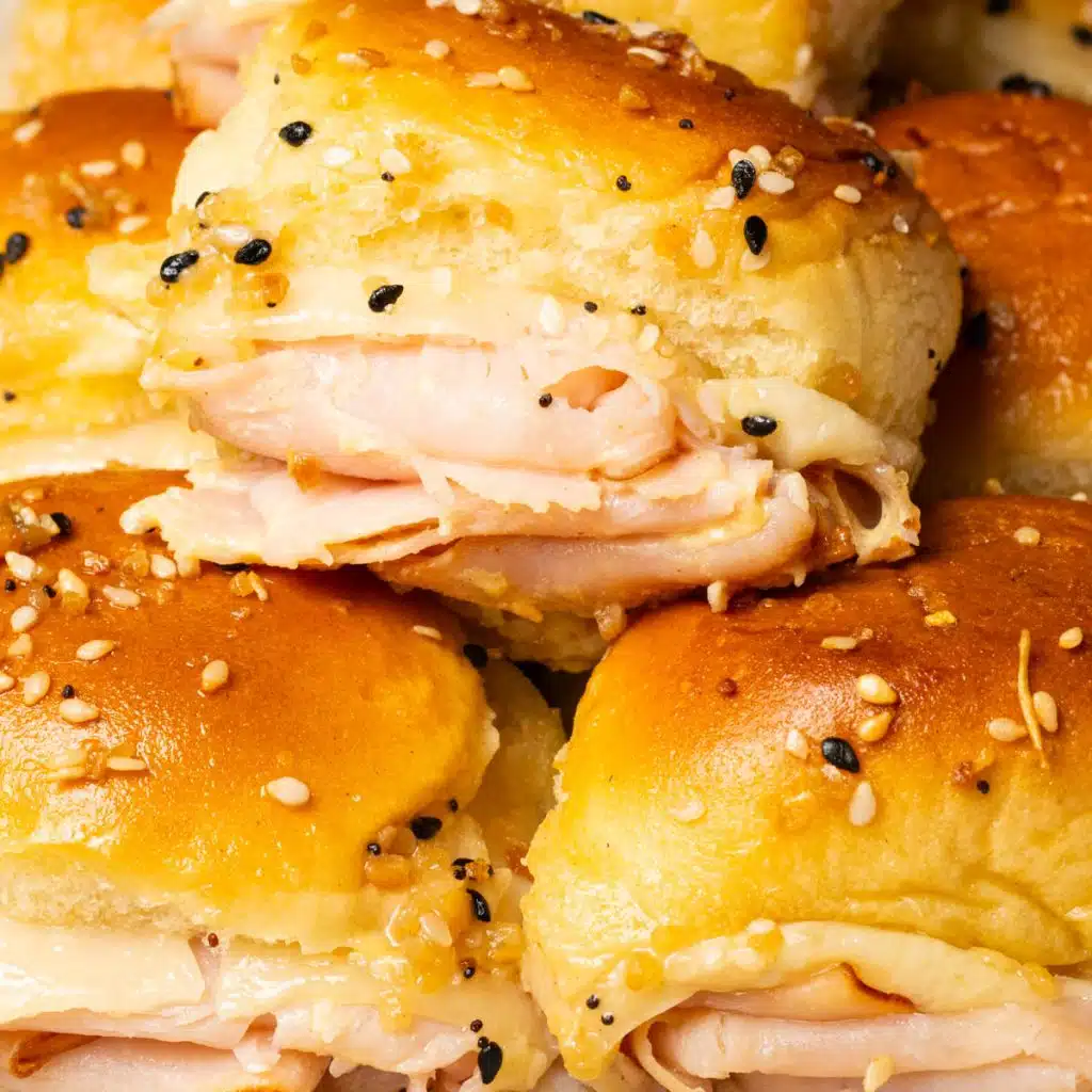 A few turkey slider on Hawaiian rolls stacked on top of each other.