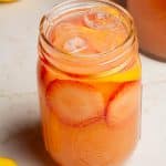 Homemade strawberry lemonade in a pint mason jar with strawberry and lemon garnish.