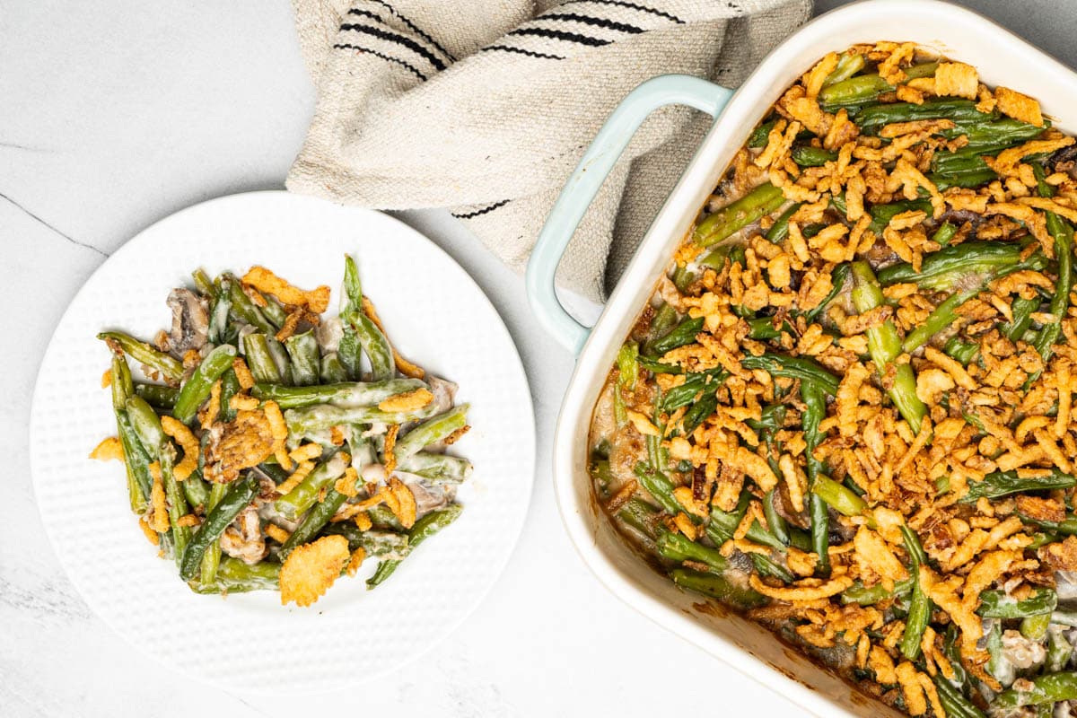 An overhead view of fresh green bean casserole in a baking dish with a small plate of green bean casserole.
