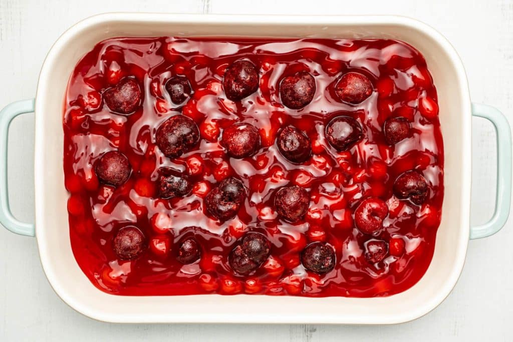 Cherry pie filling with frozen cherries in a rectangular baking dish.