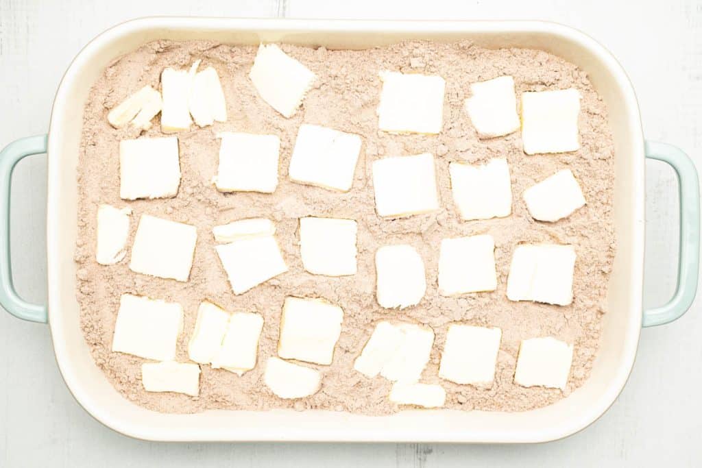 Cake mix and butter slices in a rectangular baking dish.