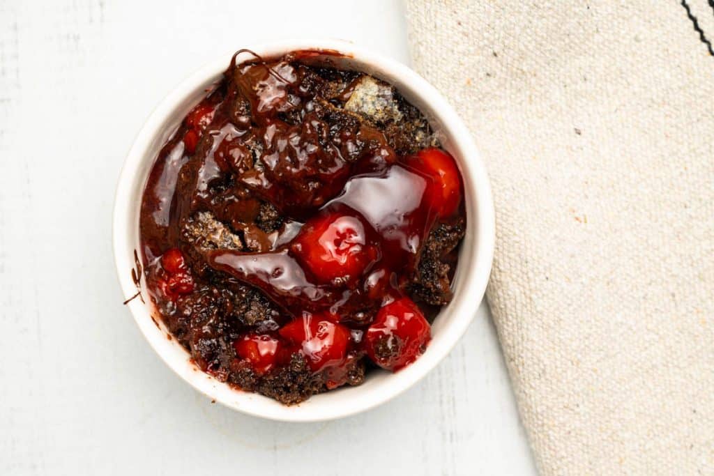 Chocolate cherry dump cake in a small white ramekin.
