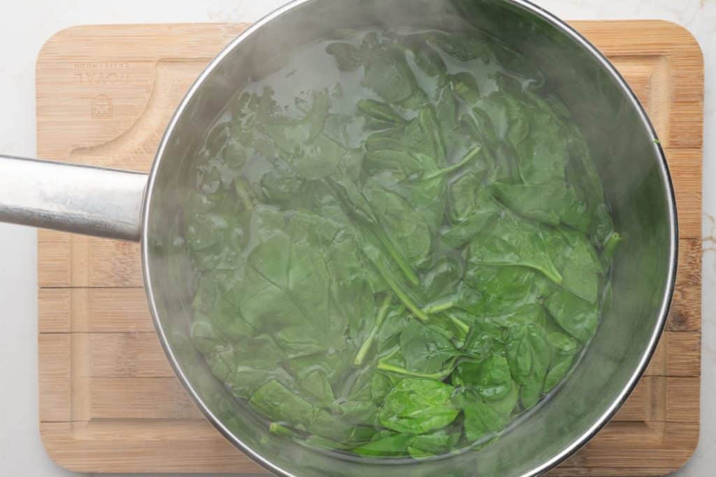 Wilted spinach in a medium saucepan.