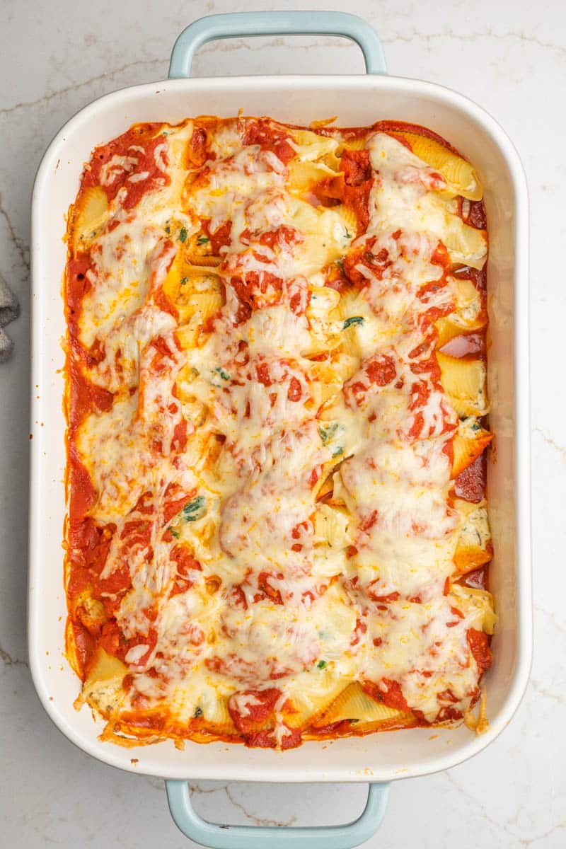 Overhead view of stuffed shells with ricotta cheese and spinach in a rectangular baking dish.