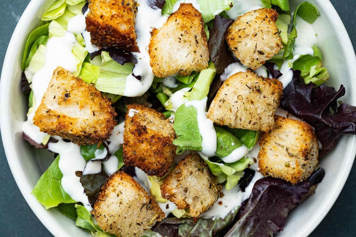 A round bowl of salad with air fryer croutons.
