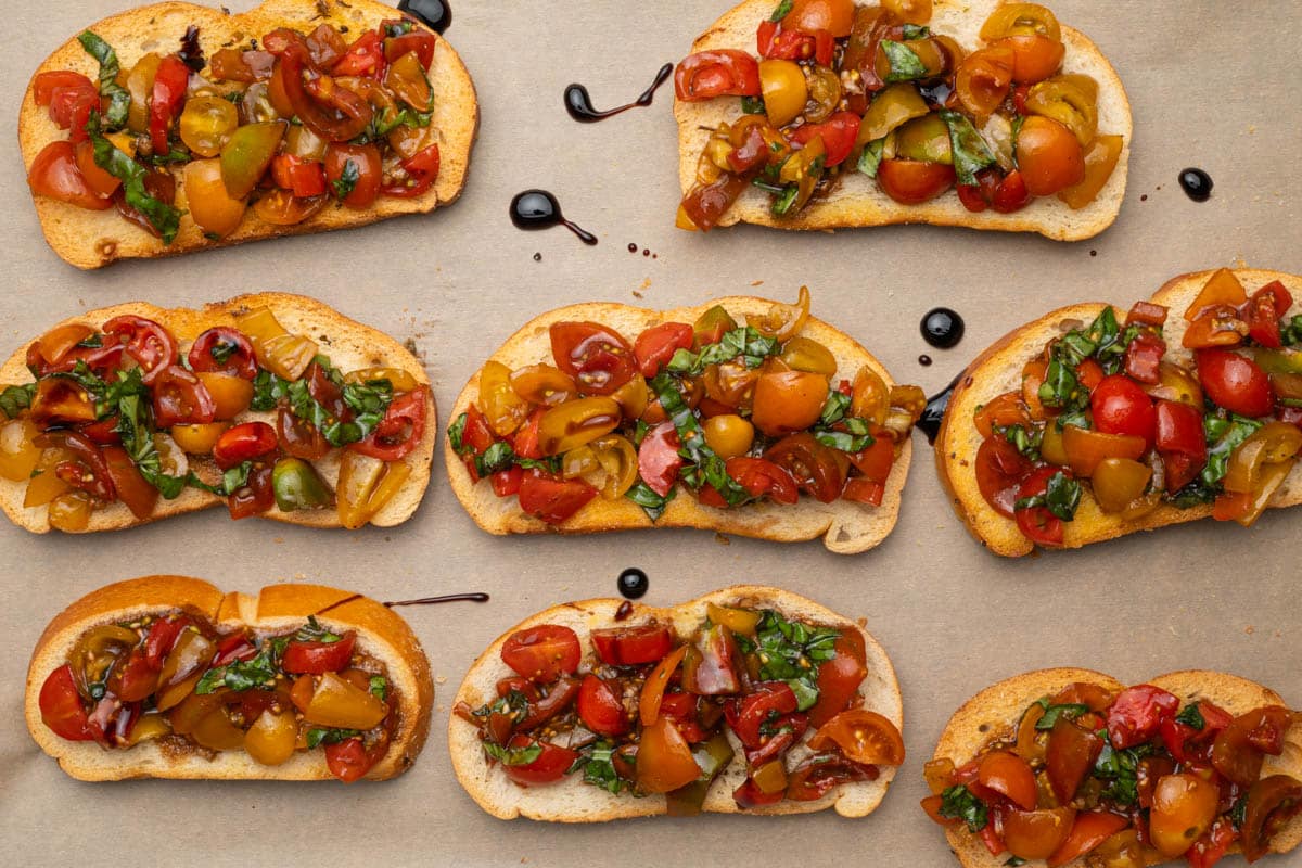 Balsamic bruschetta on parchment paper drizzled with balsamic glaze.
