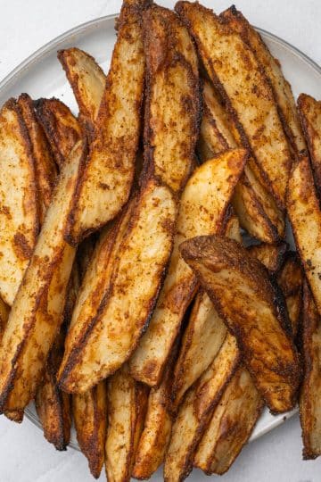 Oven roasted potato wedges on a round plate.